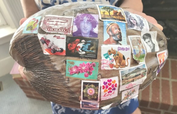 A coconut covered in postage stamps and ready to be mailed.